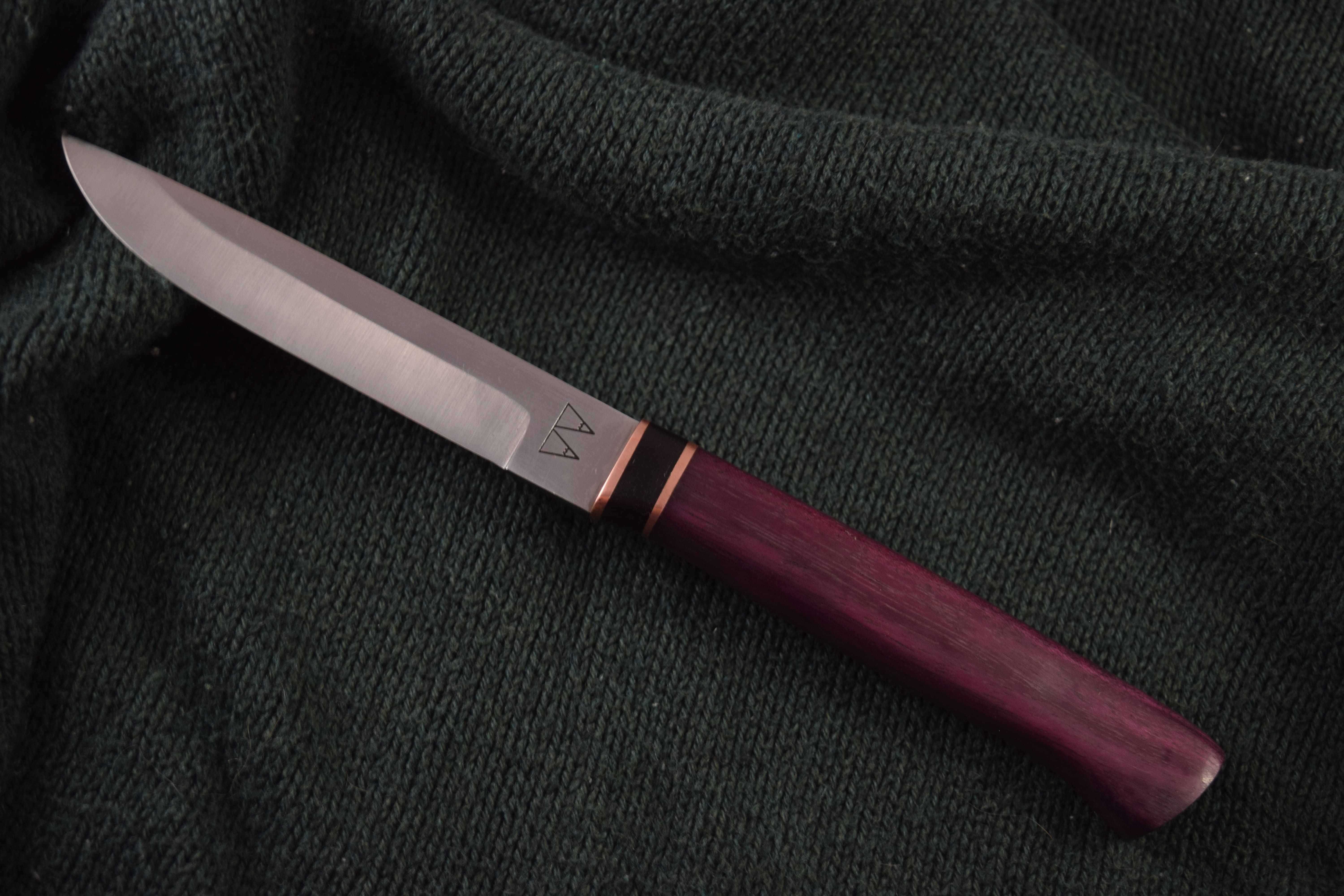 A Puukko (Traditional Finnish) knife with a Purple Heart handle and a layered Copper and Ebony bolster. A Puukko (Traditional Finnish) knife with a Purple Heart handle and a layered Copper and Ebony bolster.
